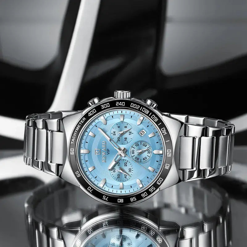 Silver wristwatch with a blue face on a reflective surface