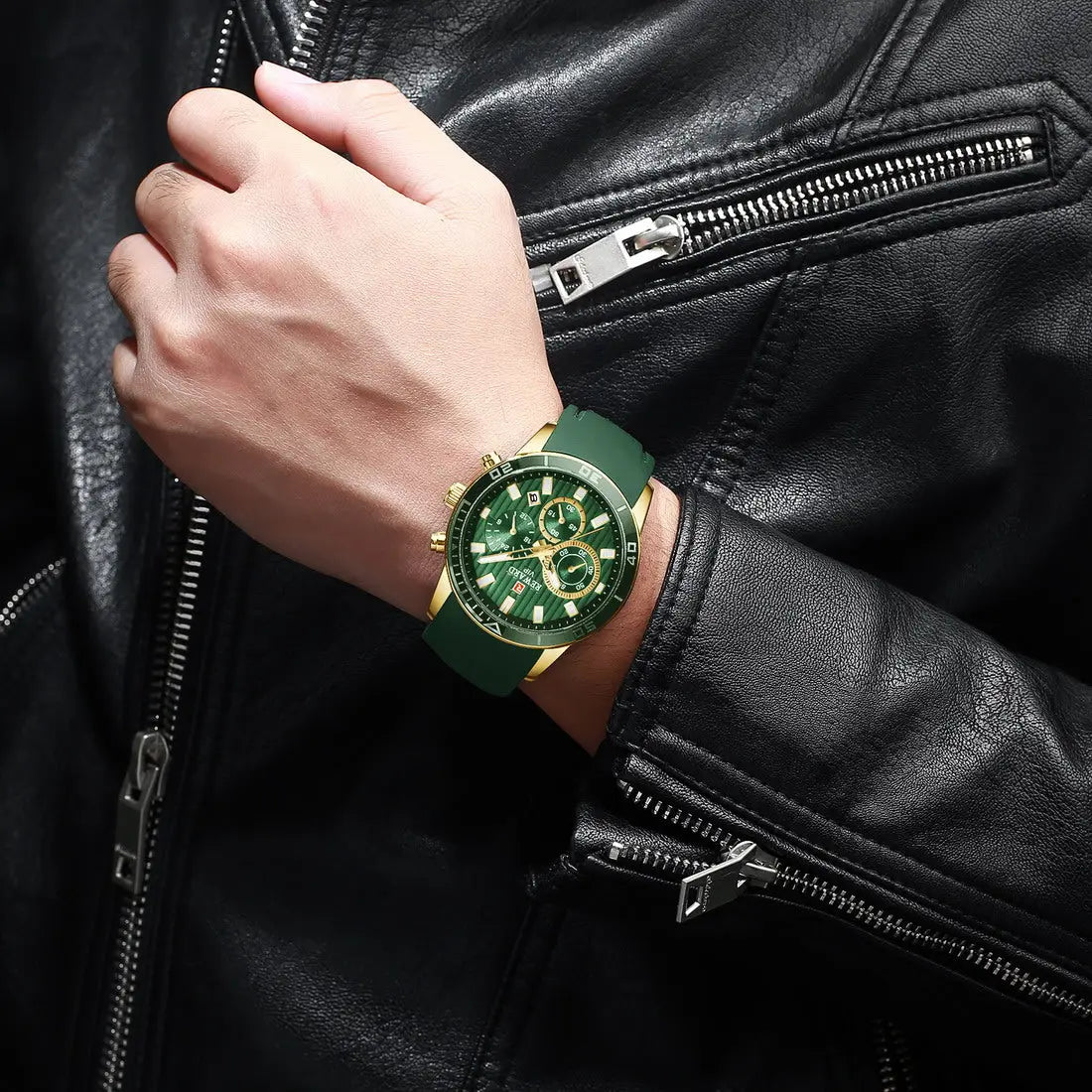 Hand wearing a green watch with gold accents on a black leather jacket.