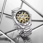 Silver wristwatch with a black and gold face on a reflective surface with geometric background