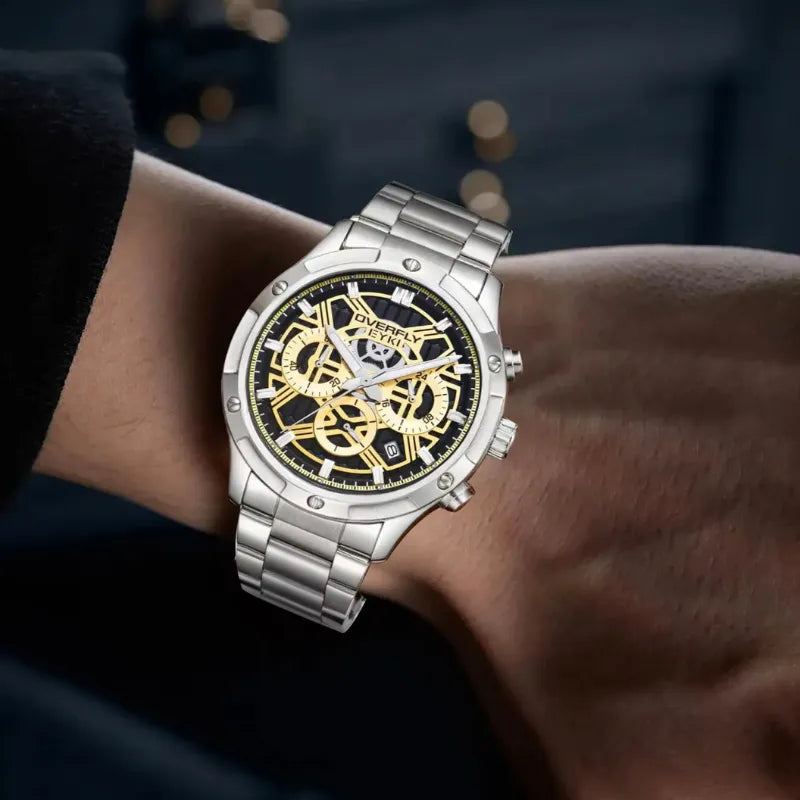 Silver watch with black and gold face on a wrist against a dark background
