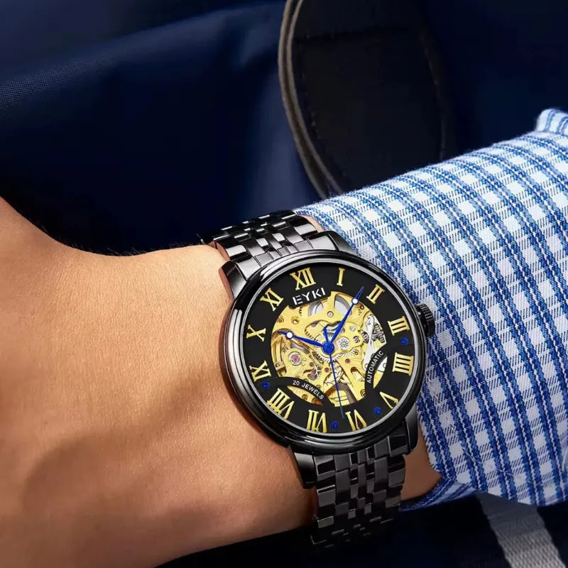 Close-up of a person wearing a black wristwatch with a blue and white checkered shirt sleeve.
