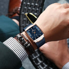 Person wearing a blue wristwatch with a leather strap on a blurred background
