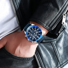 Hand wearing a blue and silver watch with a black leather jacket background