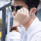 Man wearing sunglasses and a watch, with a blurred outdoor background