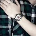 Person wearing a silver wristwatch with a checkered shirt