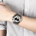 Person wearing a silver watch with a white face on a striped shirt background