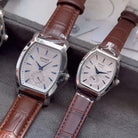 Two Jiusko watches with brown leather straps on a gray surface.