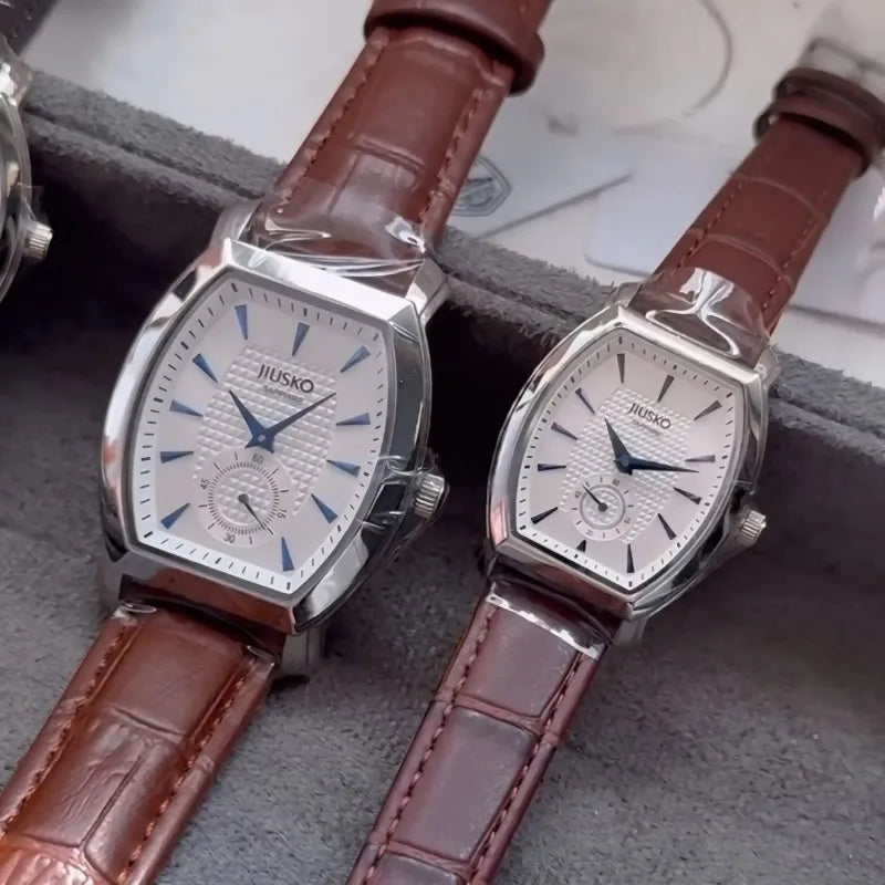 Two Jiusko watches with brown leather straps on a gray surface.