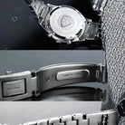 Close-up of a silver watch with brand logo and 'Stainless Steel' text on a textured surface.
